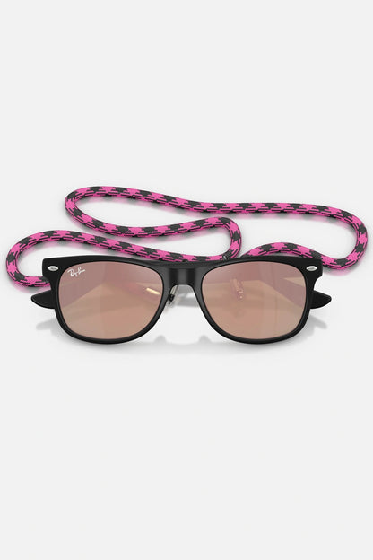 Occhiali da sole Ray-Ban RJ9052S 7028/7J Junior, montatura nero opaco su trasparente con lenti rosa specchiate.